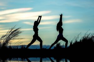 Silhoutte von 2 Frauen, die in der ruhigen Natur Yoga machen. Titelbild.